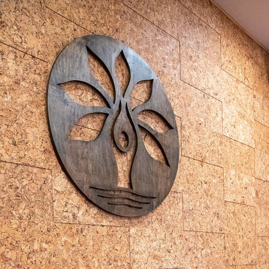 A textured wall tile made from alternating thicknesses of desert cork wall tiles in a yoga studio with a dark brown wood logo hanging on the wall.