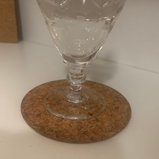 Close-up of a clear wine glass resting on a cork coaster.