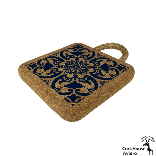 A side view of the cork hot pad features a rope handle for hanging and a cobalt blue traditional tile pattern.