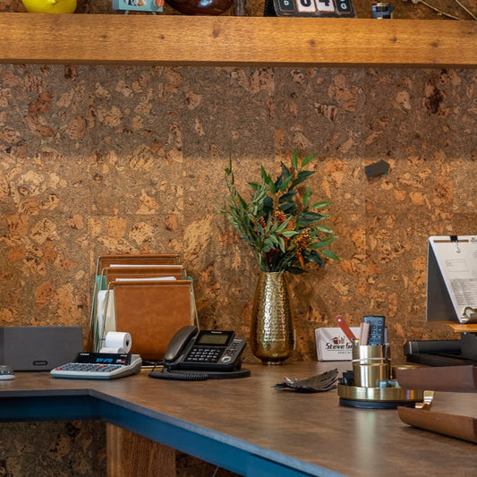 Corkstone wall tiles in an office with a wood desk and shelf and a gold vase holding a green plant.
