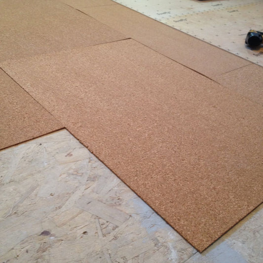QuietCork underlayment being installed over the subfloor and beneath plywood prior to flooring install