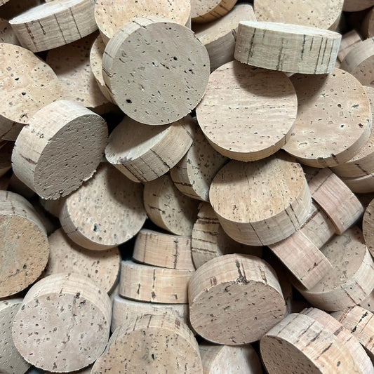 A pile of round cork rings in natural tan tones showing the texture and grain lines.