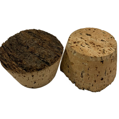 Two natural cork stoppers, showing a closeup of the dark, rough, natural texture of the top and smooth, refined surface of the bottom.