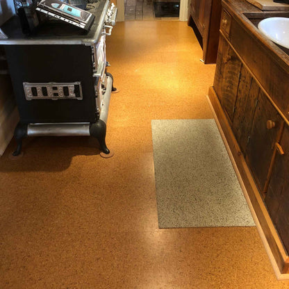 Pebble floating cork floor tiles in a kitchen, with a rubber cork mat in front of the sink and a vintage stove on furniture pads