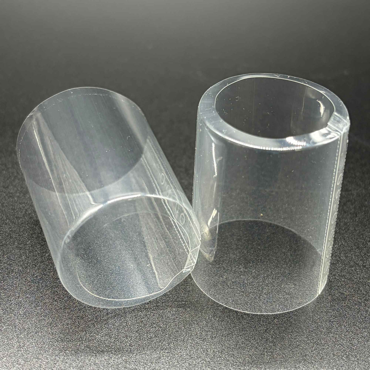 Two transparent, open cap PVC shrink caps with vertical perforation