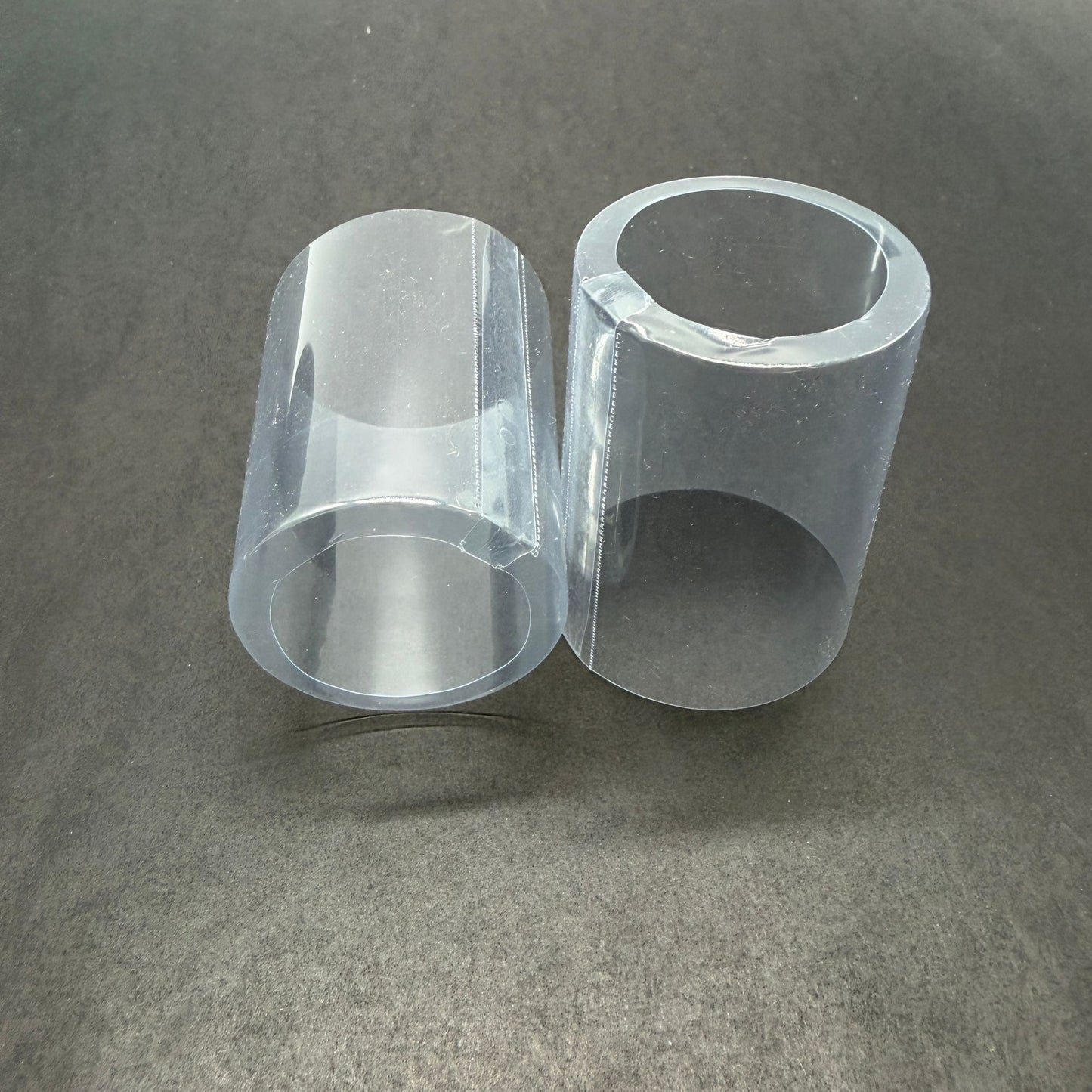 Close-up view of two clear shrink caps with open tops 
