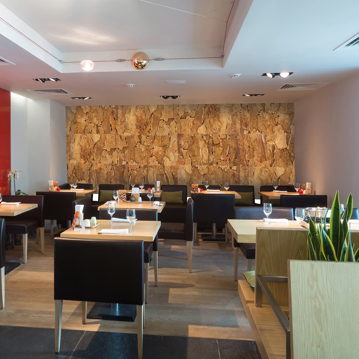 Modern restaurant interior with tables, chairs, and Arizona cork wall tiles as an accent wall along the back of the restaurant.
